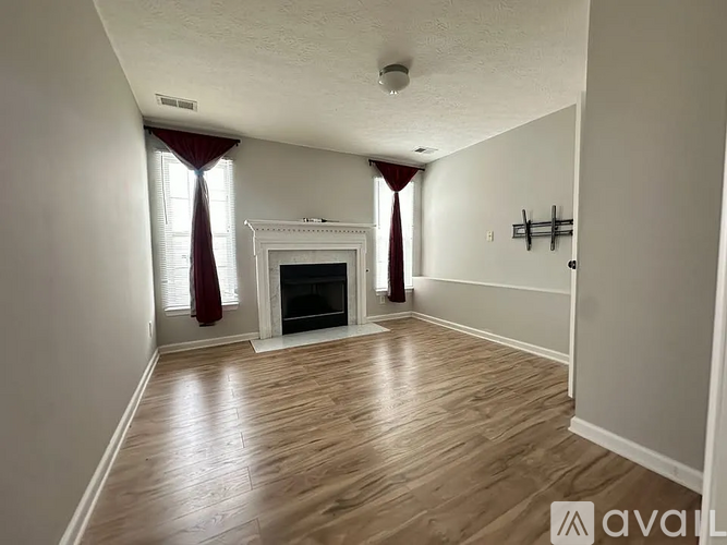 A living room with a fireplace and wooden floors.