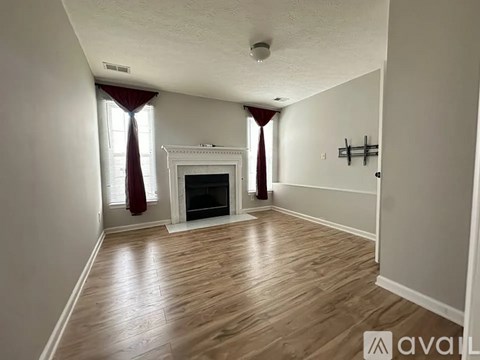 A living room with a fireplace and wooden floors.