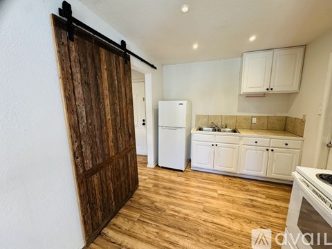 A kitchen with white appliances and wooden floors.