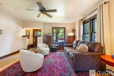 A living room with a brown couch and a ceiling fan.