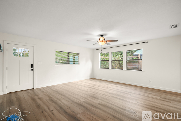A room with a ceiling fan and a door leading to another room.