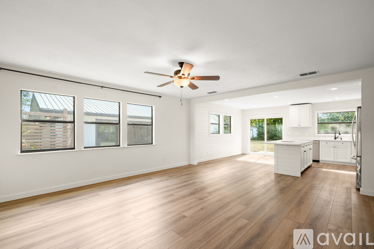 A spacious room with wooden floors and a ceiling fan.