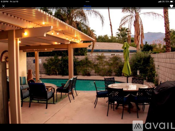 A patio with a table, chairs, and a pool.