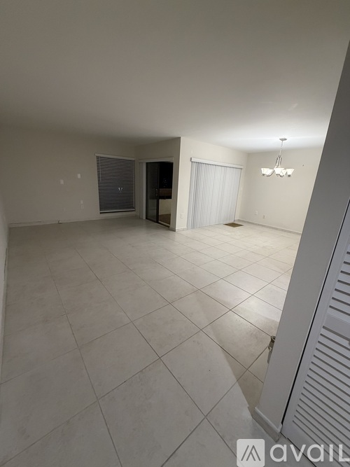 A spacious room with a tiled floor and a chandelier hanging from the ceiling.