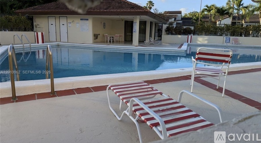 A pool with red and white striped sun loungers.