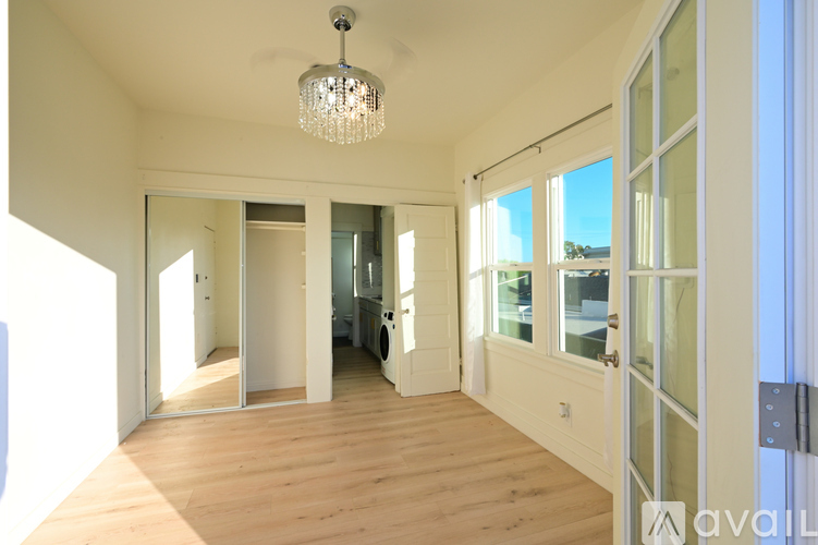 A well-lit, spacious room with wooden floors and a chandelier hanging from the ceiling.