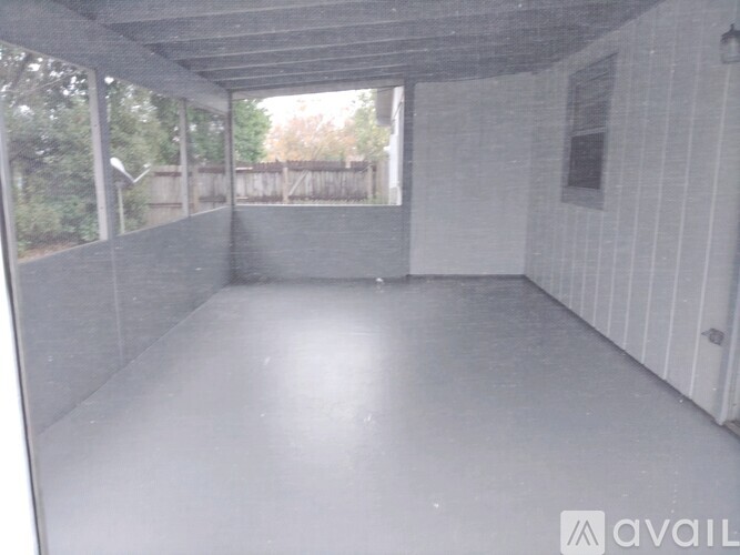 A spacious room with a white wall and a window.