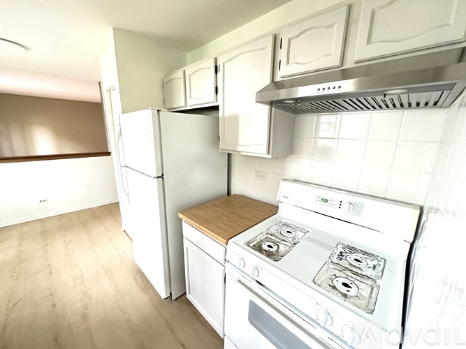 A white kitchen with a stove and refrigerator.