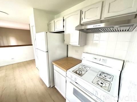 A white kitchen with a stove and refrigerator.