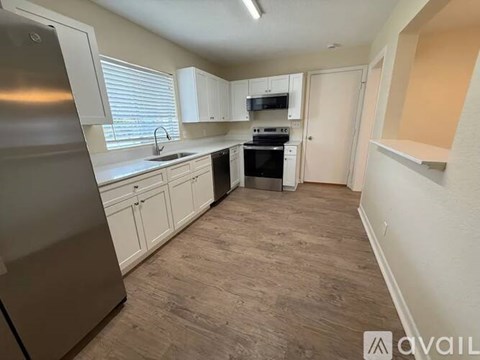 A kitchen with white cabinets and a stainless steel refrigerator.