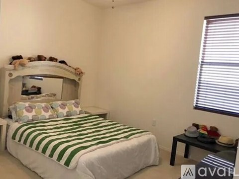 A bedroom with a white bed and a green and white striped blanket.