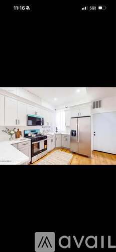 A modern kitchen with white cabinets and a wooden floor.