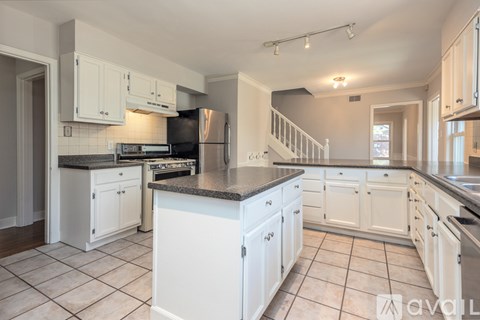 A kitchen with white cabinets and a black fridge.