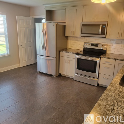 A kitchen with a refrigerator, oven, and microwave.