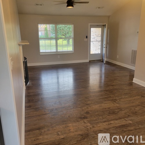 A spacious room with wooden flooring and a ceiling fan.