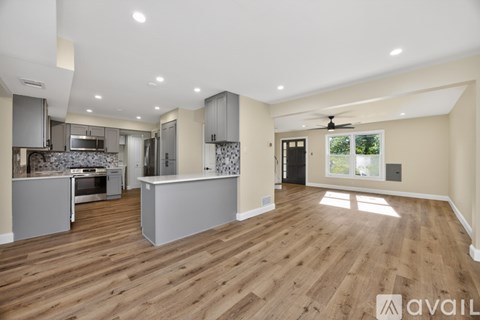 A spacious kitchen and living room with wooden flooring and modern appliances.