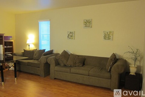 A living room with a grey couch and a table with a vase on it.