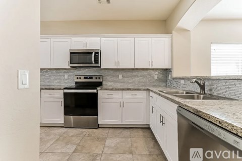 A kitchen with white cabinets and a granite countertop.