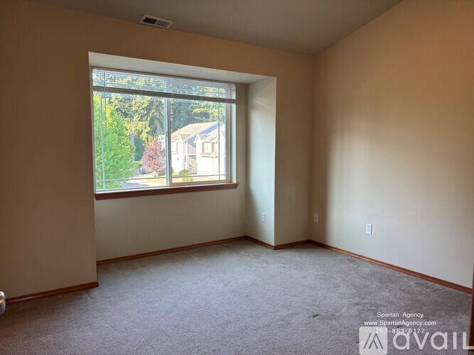 Empty room with a window showing a house and trees outside.
