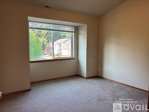 Empty room with a window showing a house and trees outside.