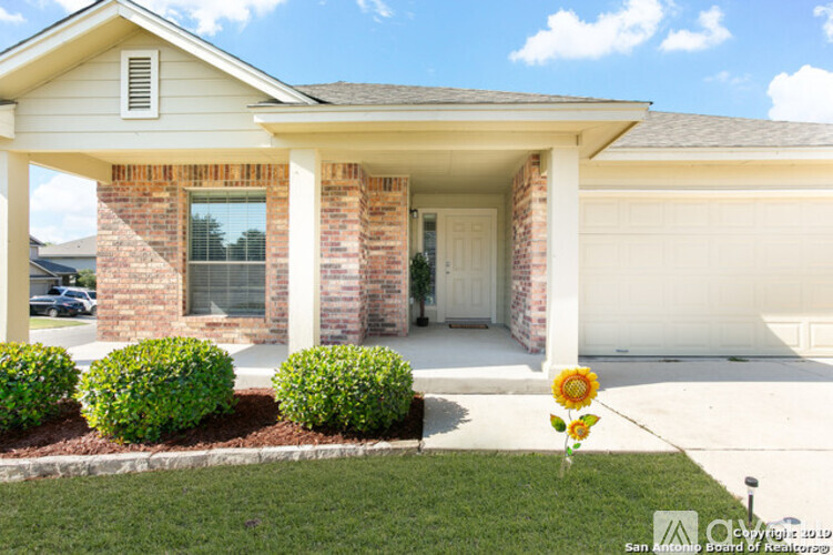 A house with a white garage door and a sunflower in front.