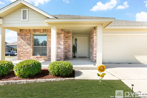 A house with a white garage door and a sunflower in front.