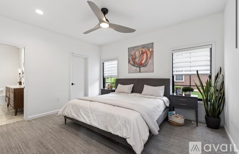 A bedroom with a large bed, a ceiling fan, and a potted plant.
