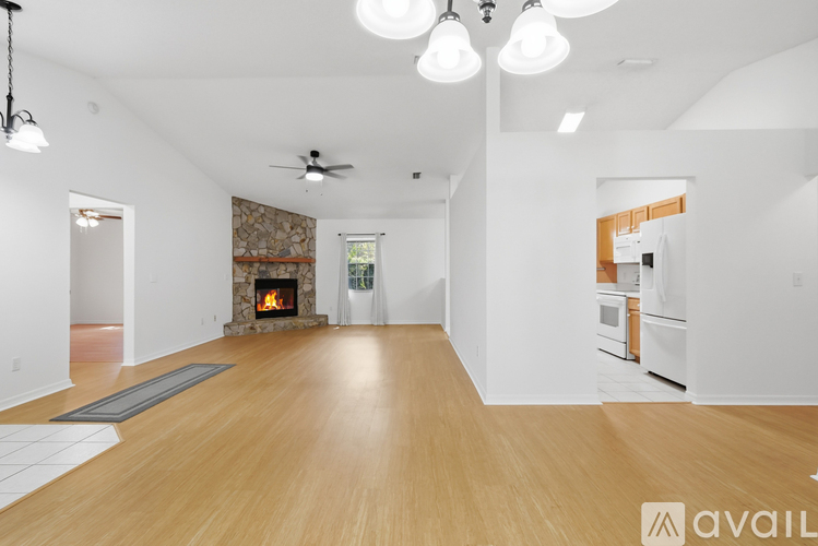 A spacious living room with a fireplace and a ceiling fan.