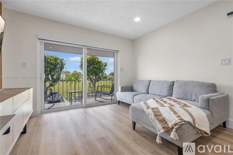 A living room with a grey couch and a sliding glass door leading to a backyard.
