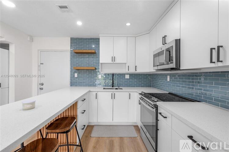 A modern kitchen with white cabinets and a blue tile backsplash.