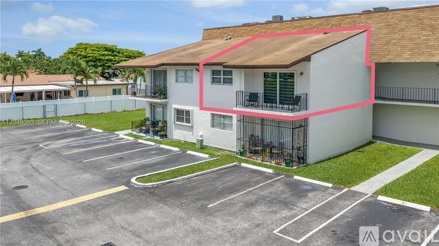 A parking lot in front of a white building with a red line drawn on it.