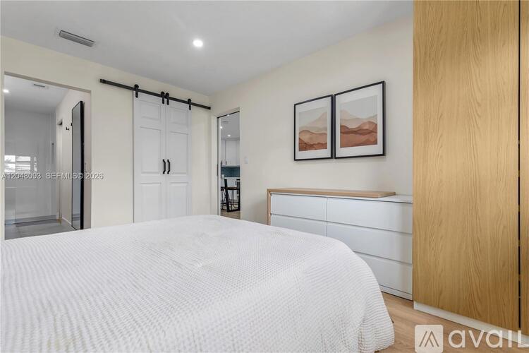 A bedroom with a white bed and two pictures on the wall.
