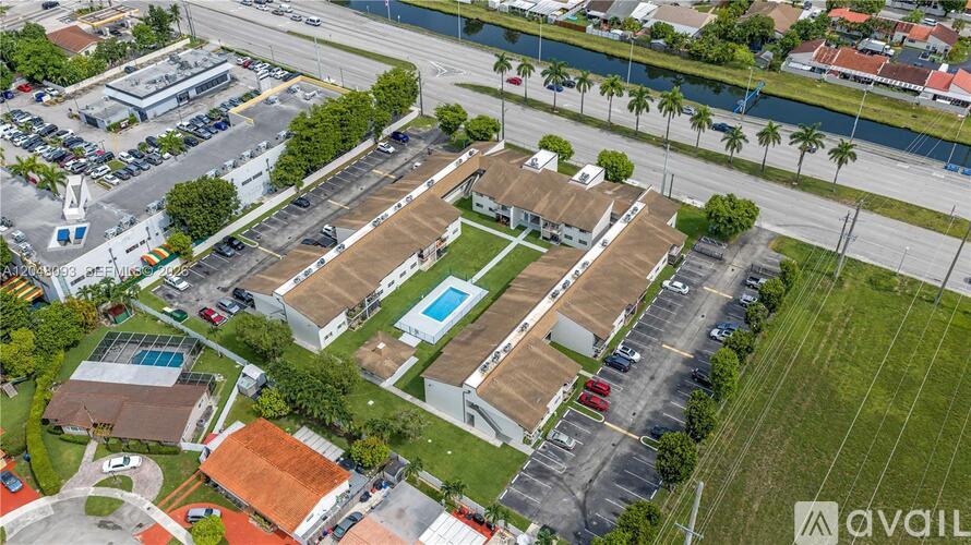 A bird's eye view of a parking lot with a building and a pool.