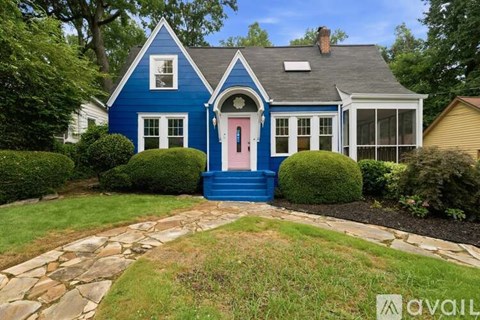 A blue house with a pink door and a stone pathway leading to it.