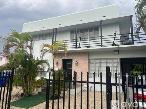 A white two-story house with a black gate in front.