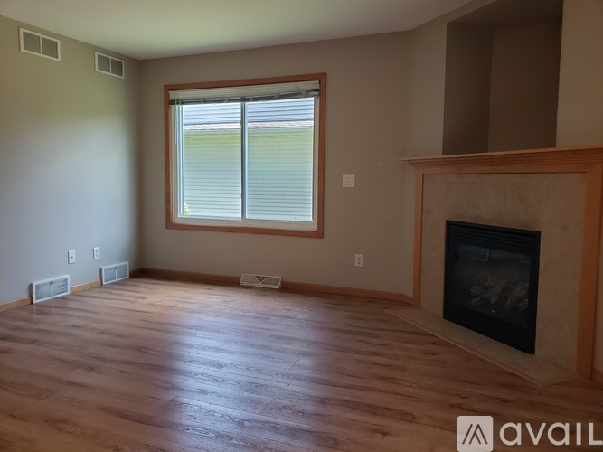 A room with a fireplace and a window with blinds.