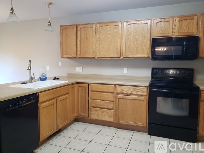 A kitchen with wooden cabinets and black appliances.