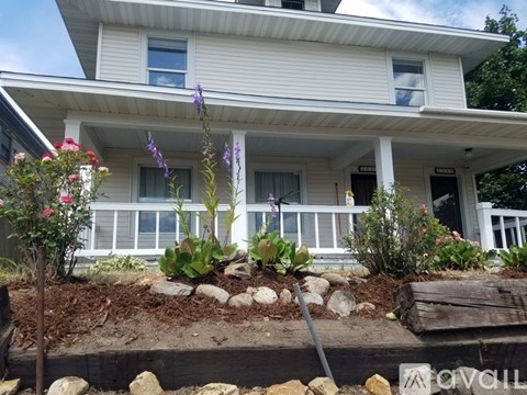 A white house with a flower bed in front.