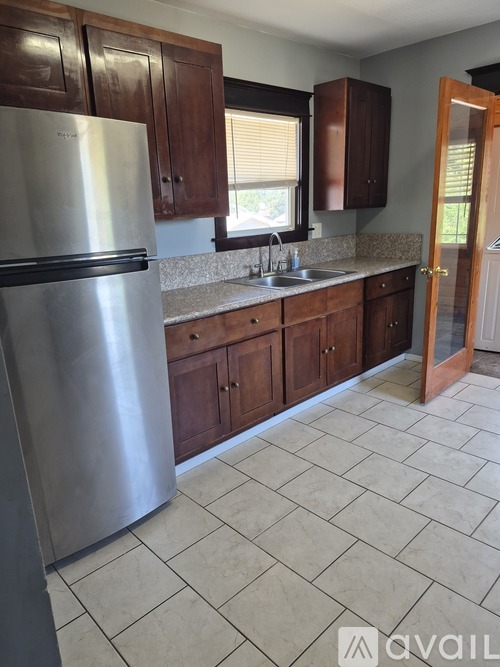 A kitchen with a stainless steel refrigerator and wooden cabinets.