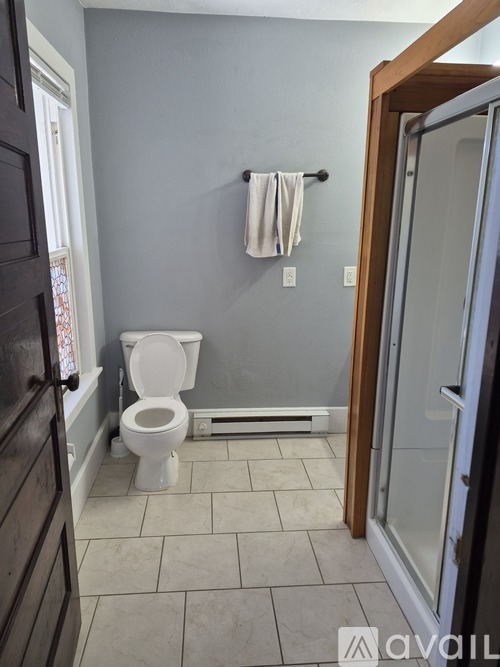 A bathroom with a toilet, a towel, and a glass door.