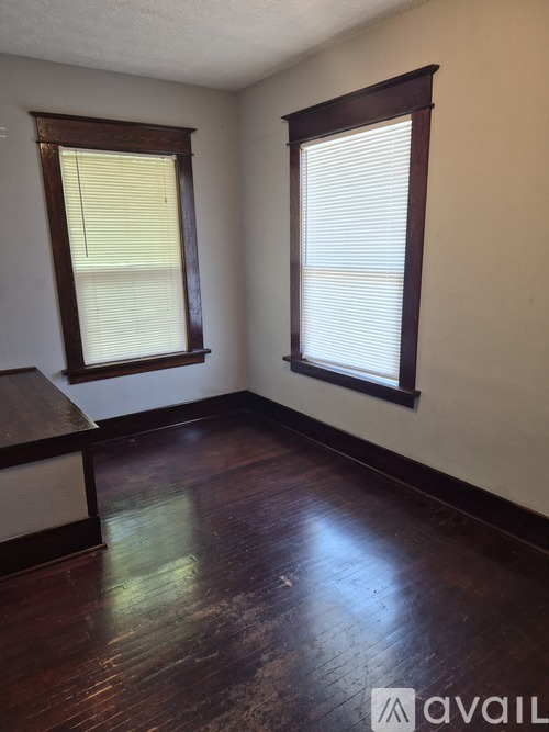 A room with wooden floors and two windows.