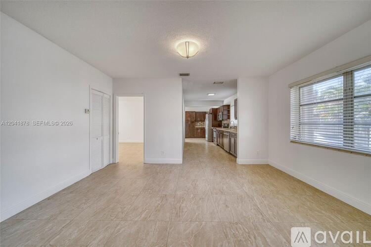 A spacious living room with hardwood floors and white walls.