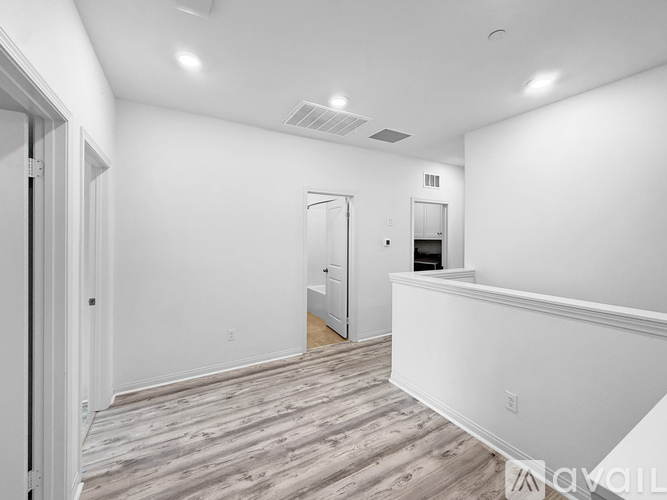A spacious room with wood flooring and white walls.