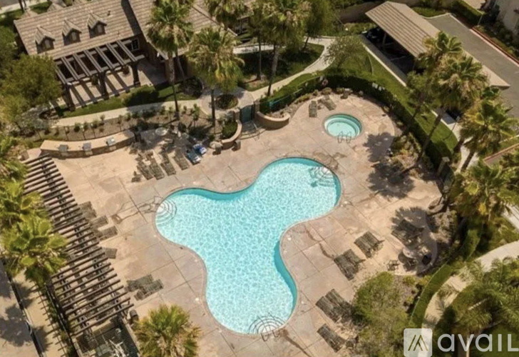 A pool surrounded by palm trees and a building.