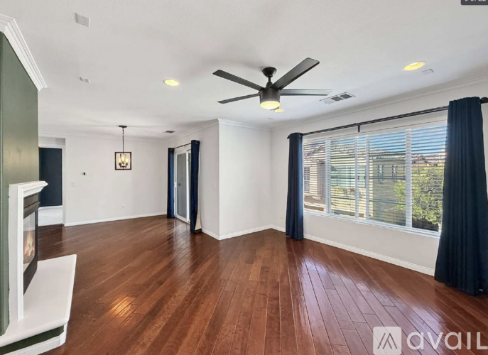 A spacious room with a ceiling fan and hardwood flooring.