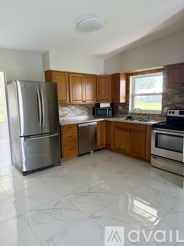 A kitchen with a refrigerator, microwave, oven, and sink.