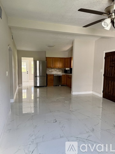 A spacious kitchen with wooden cabinets and a marble floor.