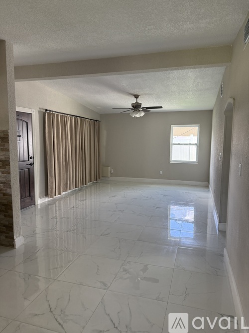 A spacious room with a marble floor and a ceiling fan.