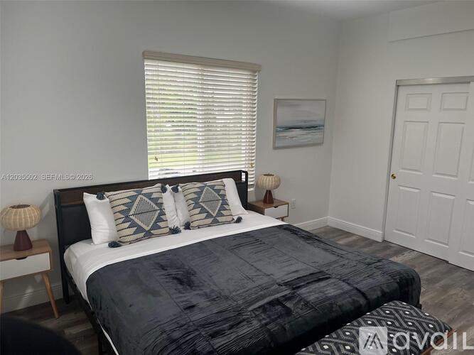 A bedroom with a large bed and a painting on the wall.
