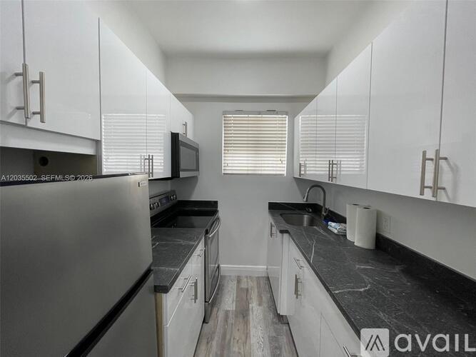 A kitchen with white cabinets and black countertops.